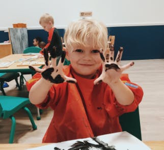Child with paint on hands in a classroom