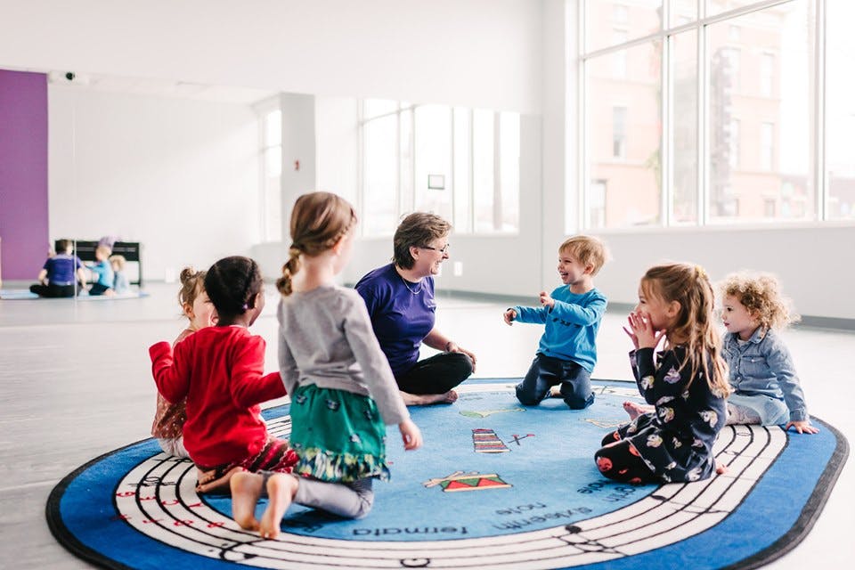 Adult and children sitting on a rug in a circle