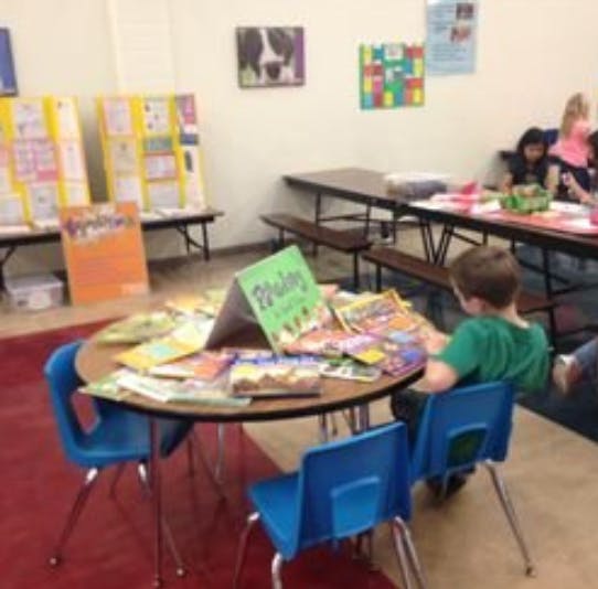 Child sitting at a round table covered with books