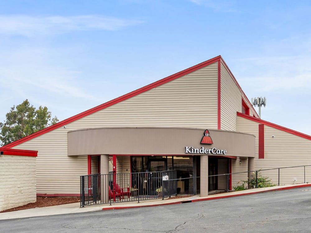 KinderCare building with light siding and red trim under a blue sky