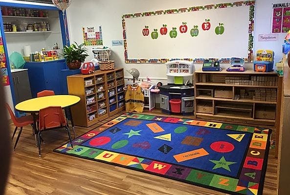 Classroom with a colorful rug, small table and chairs, and storage shelves
