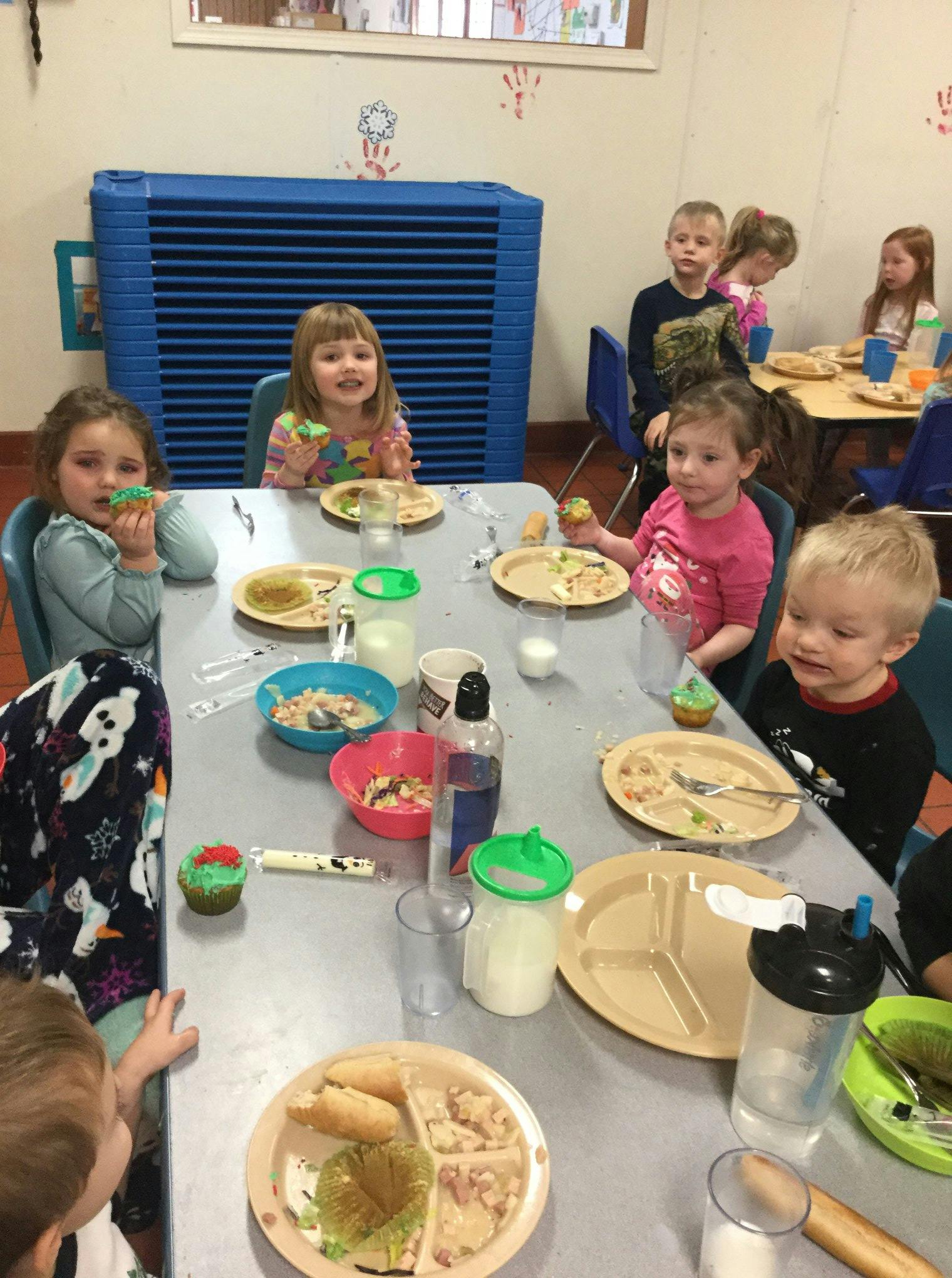 Children sitting at tables with plates of food