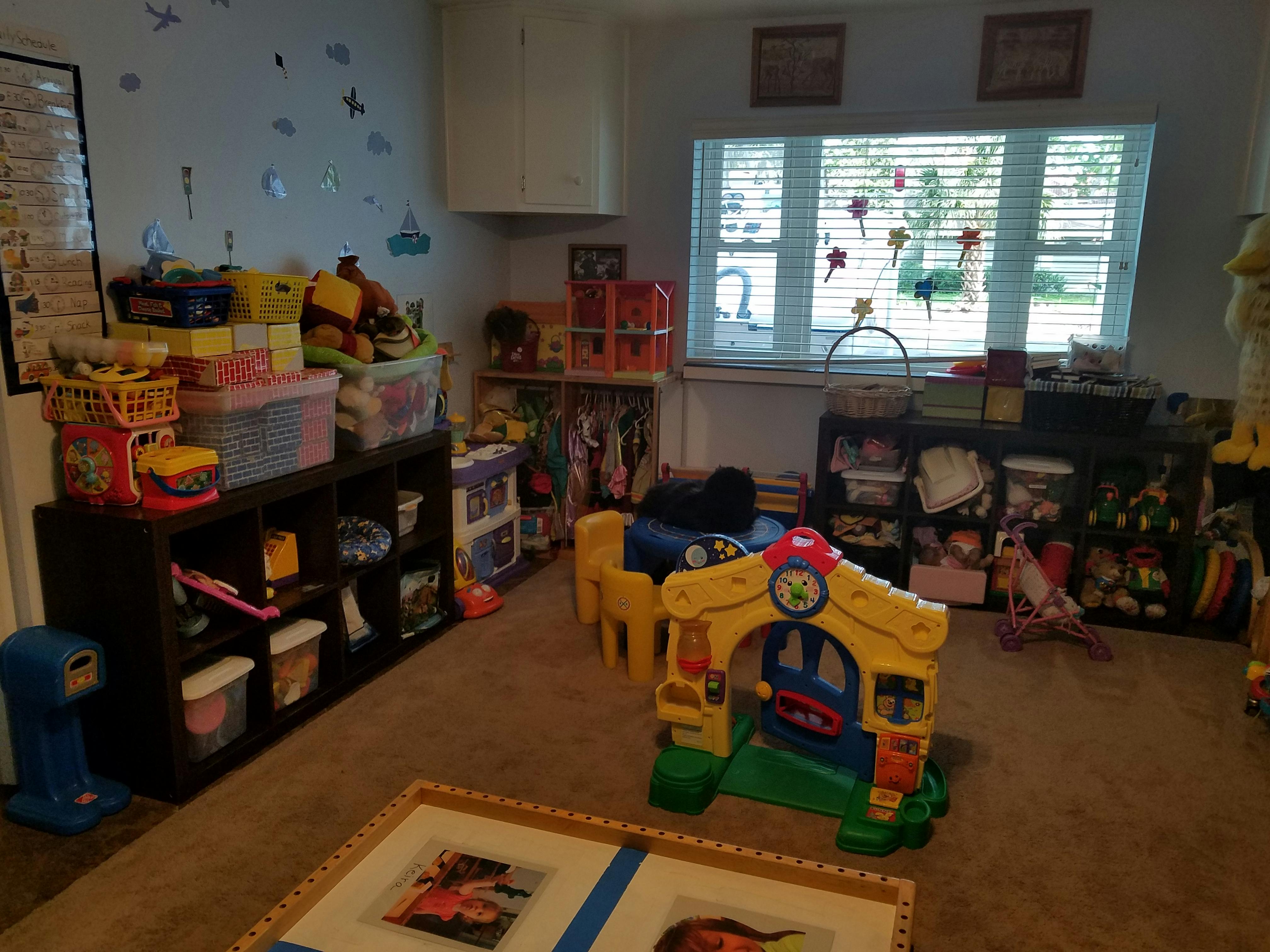 Playroom with shelves of toys and a small playhouse