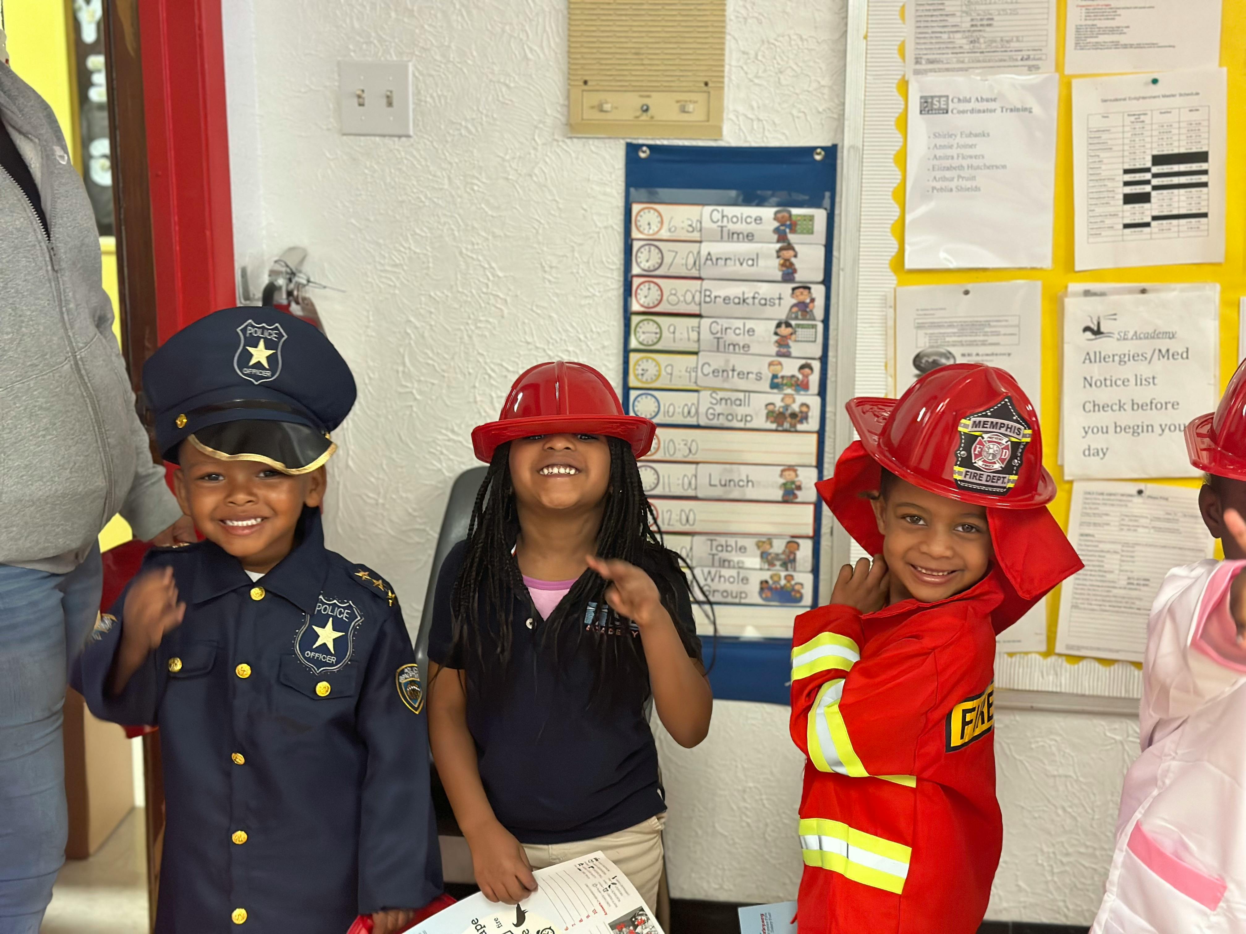Three children dressed in career costumes, including a police officer and firefighters