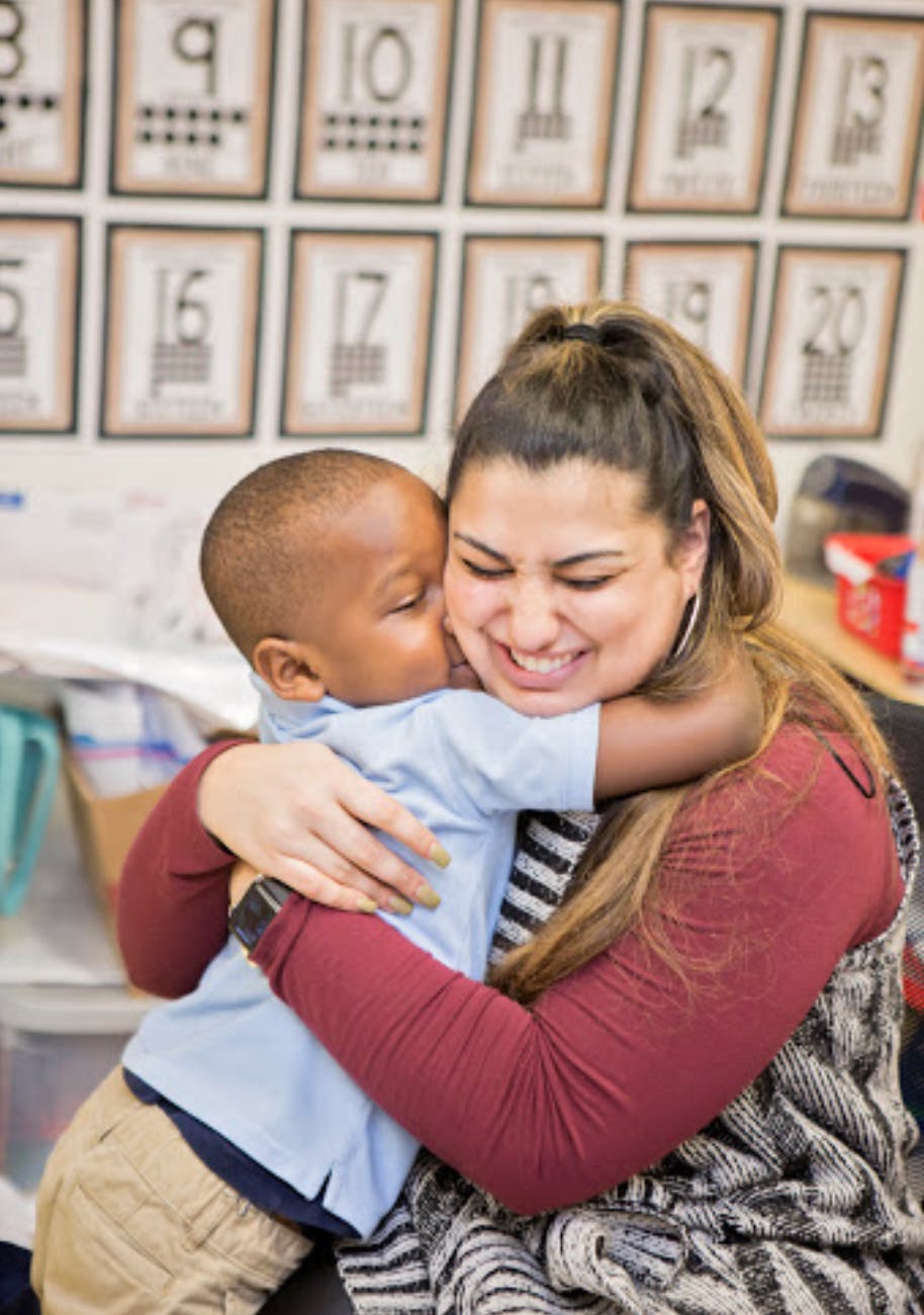 Adult person hugging a child in a classroom