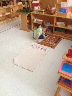 Child playing with a wooden puzzle on the floor in a classroom