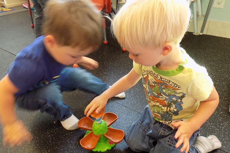 Two children playing with a toy on the floor