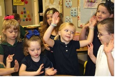 Group of children raising their hands in a classroom