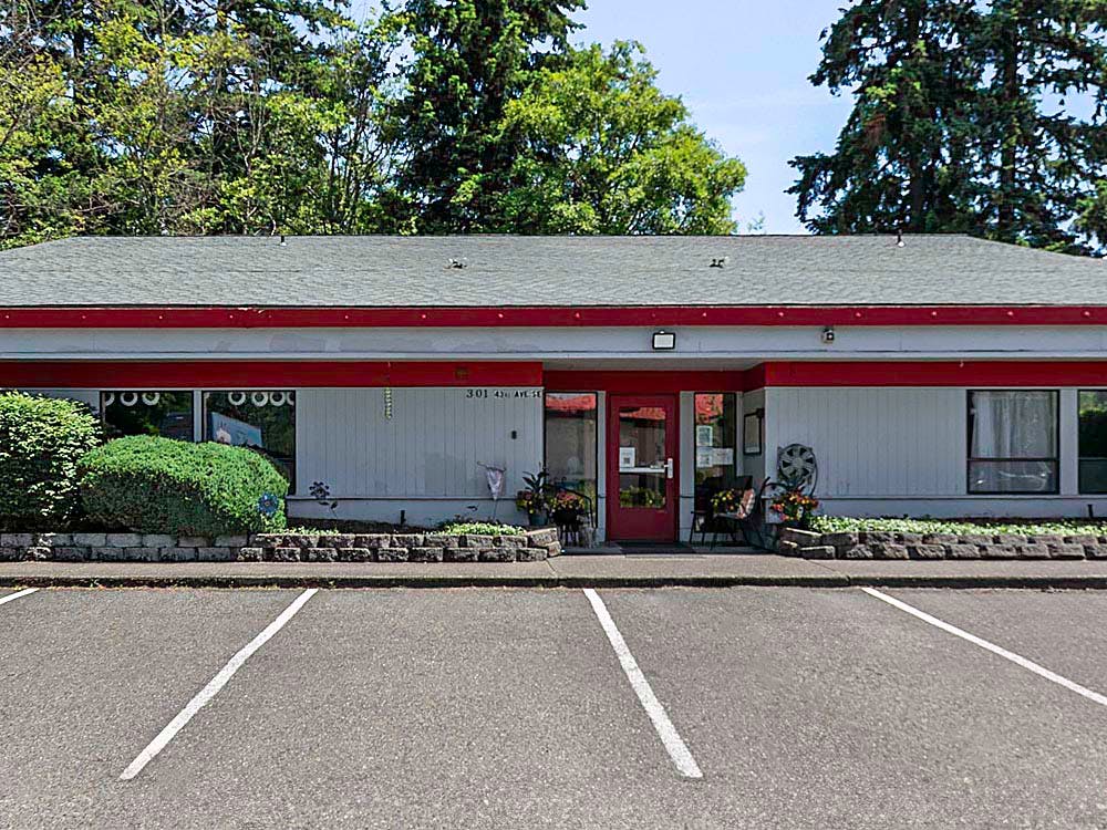 Single-story commercial building with red trim and white siding