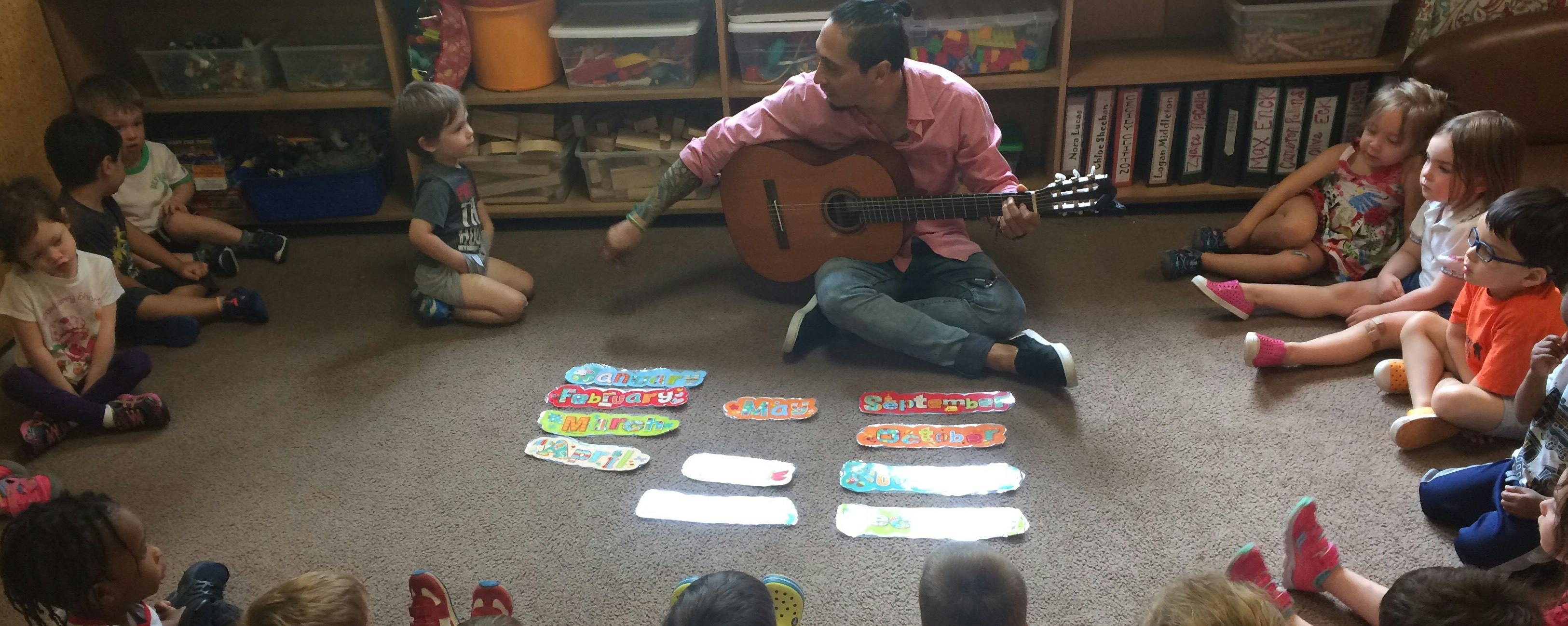 Person playing guitar for children in a classroom