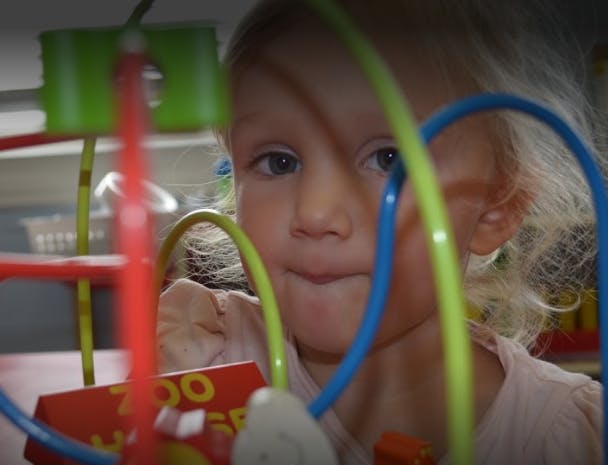Child looking through a wire maze toy