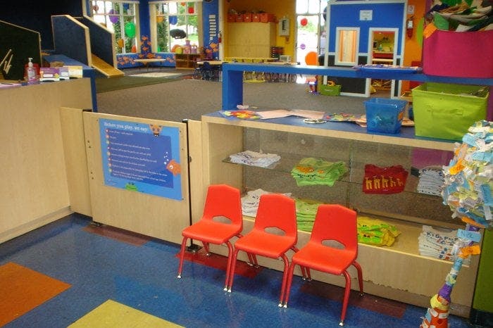 Three red chairs in a colorful classroom with play areas