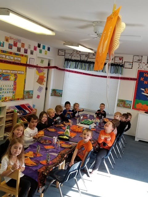 Children sitting at a long table in a classroom