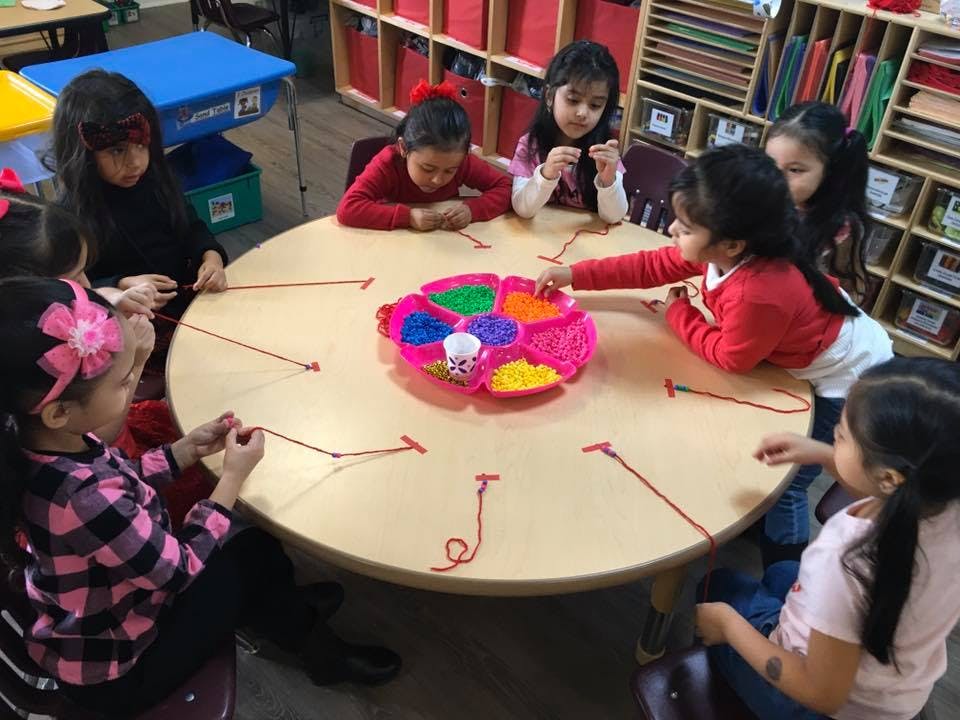Children playing a game with strings and a colorful spinner on a round table