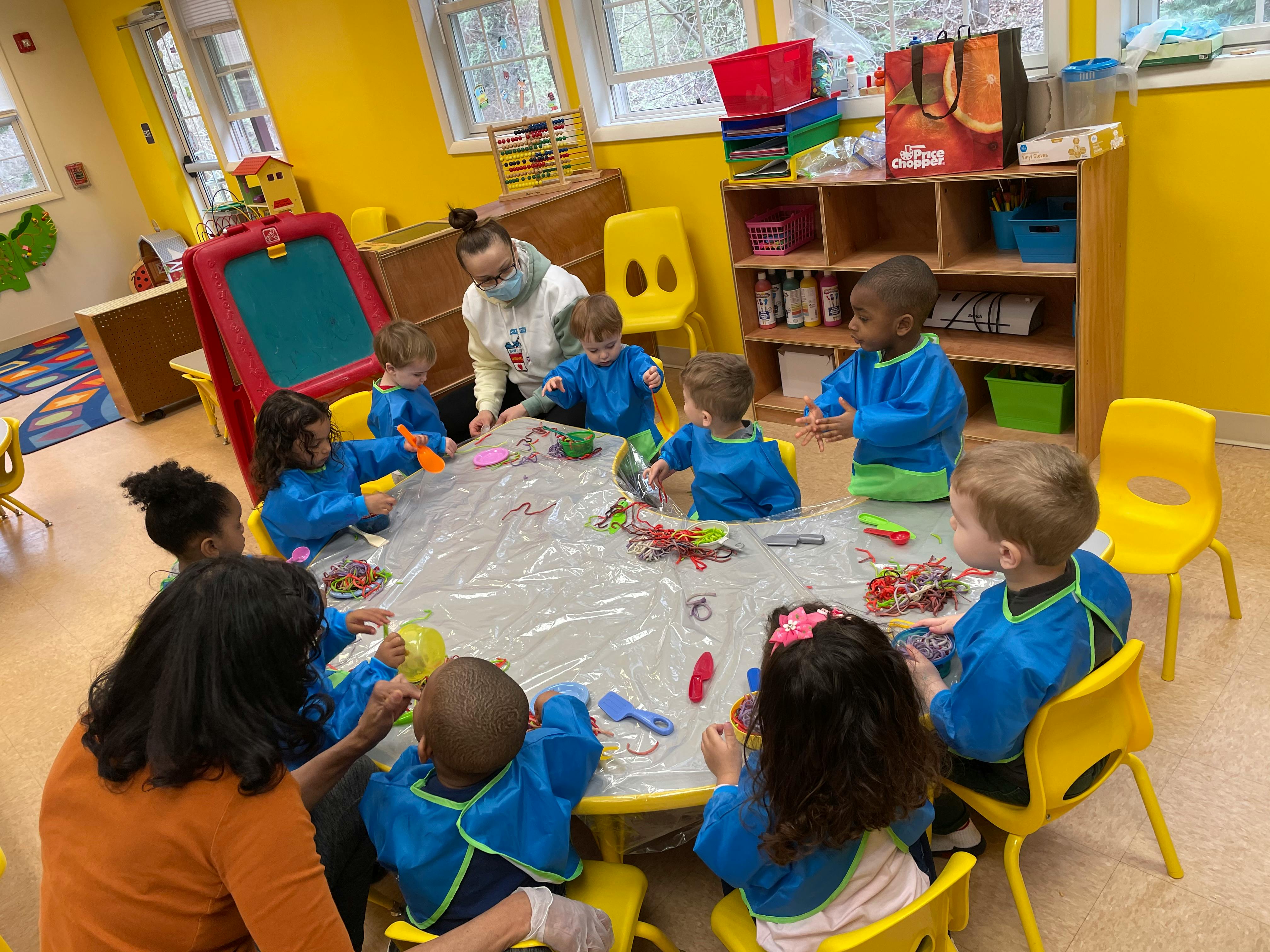 Adult and children gathered around a table in a classroom