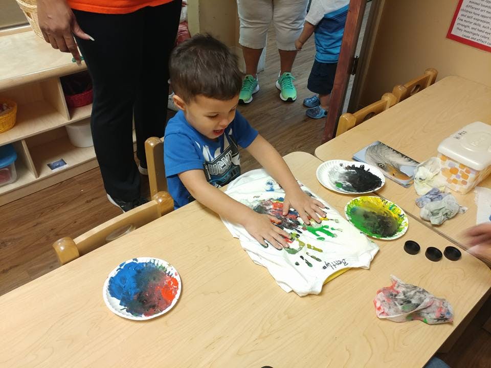 Child painting a shirt at a table