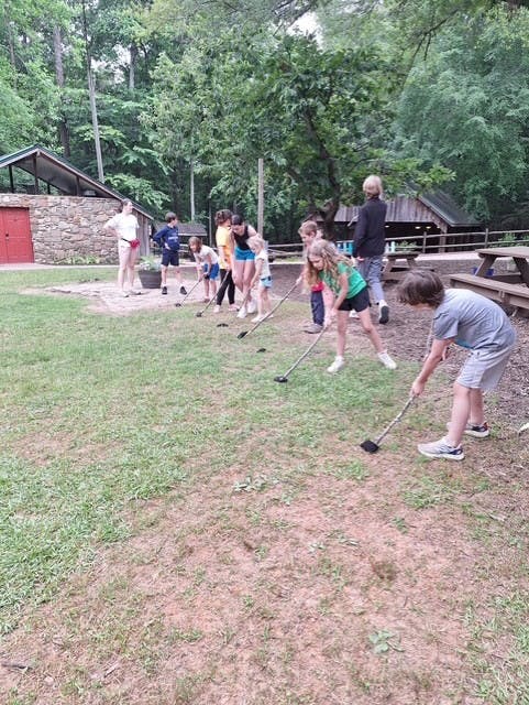 Children and adults playing golf outdoors