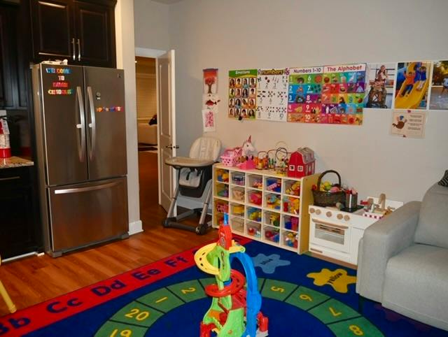 Play area with alphabet rug and toy storage in a home kitchen