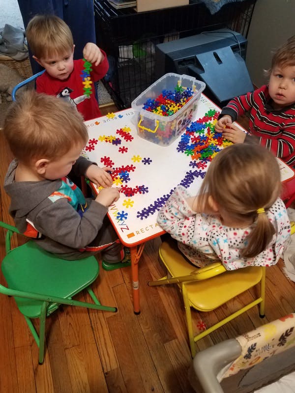 Children playing with colorful snowflake-shaped building blocks at a table