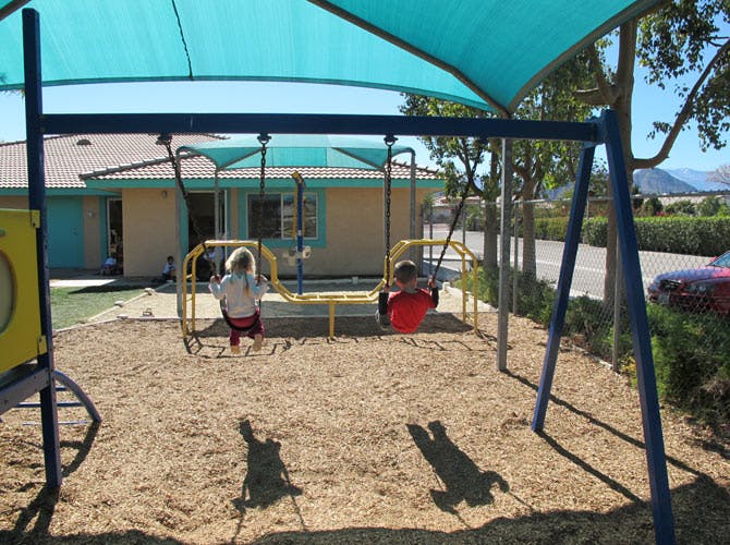 Two children on swings in a playground