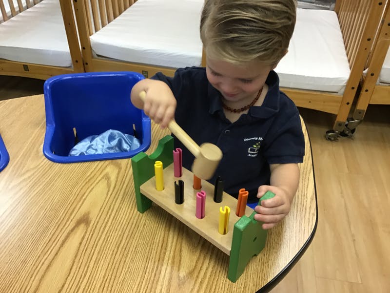 Child playing with a wooden hammer and peg toy