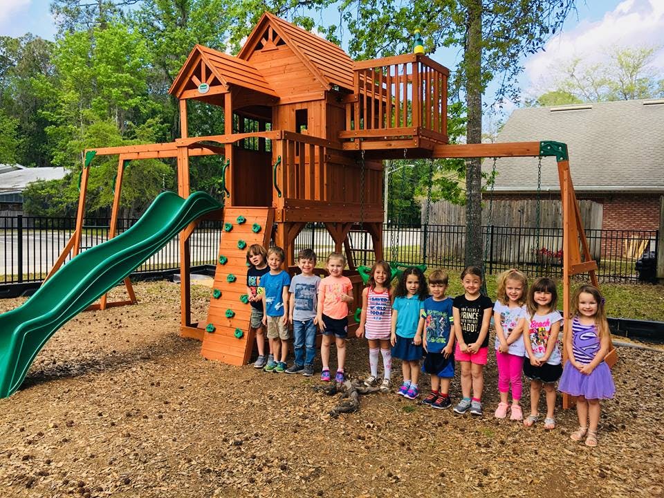 Group of children standing in front of a wooden playground structure