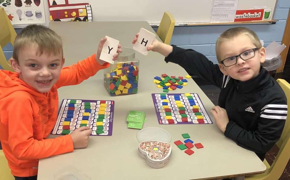 Two children playing a board game with letter cards