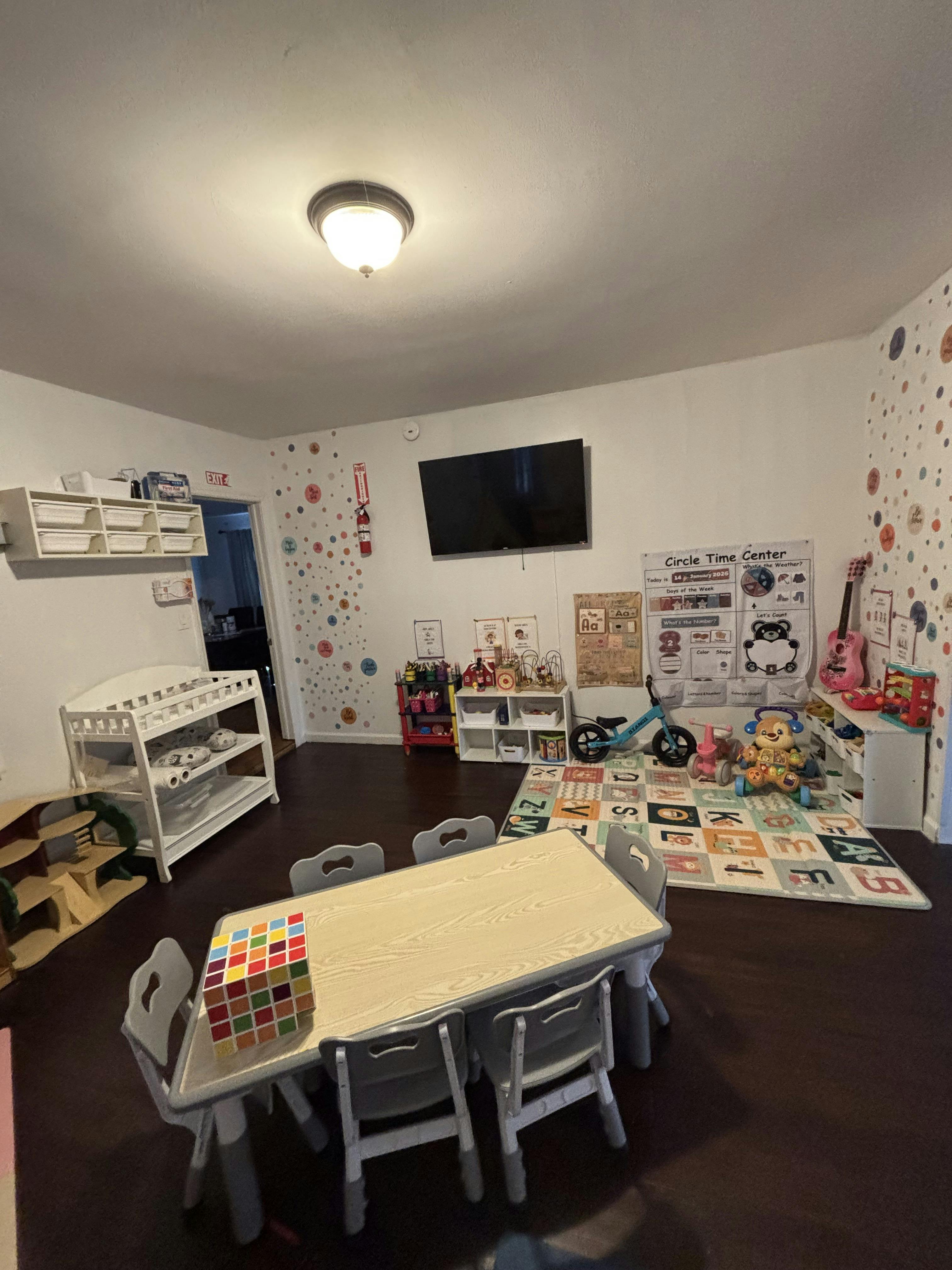Children's classroom with a table and chairs, toys, and an alphabet rug