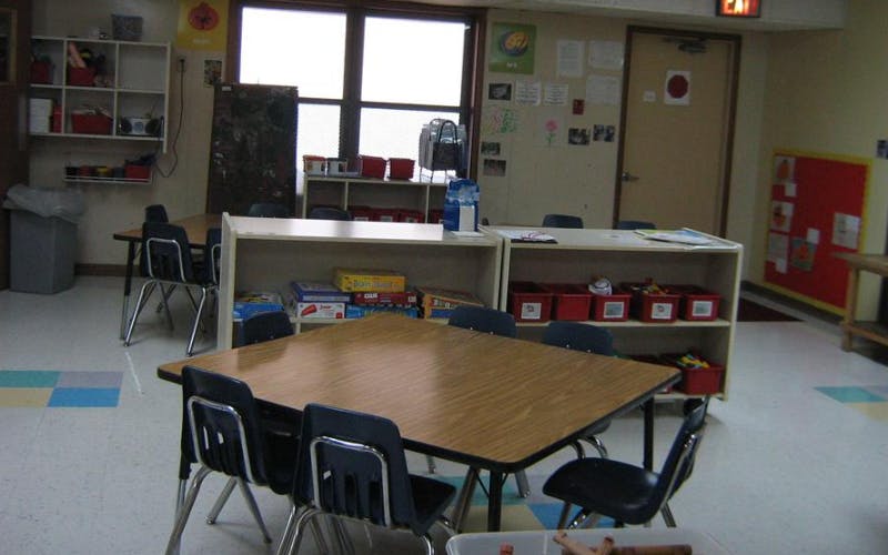 Classroom with tables, chairs, shelving units, and windows