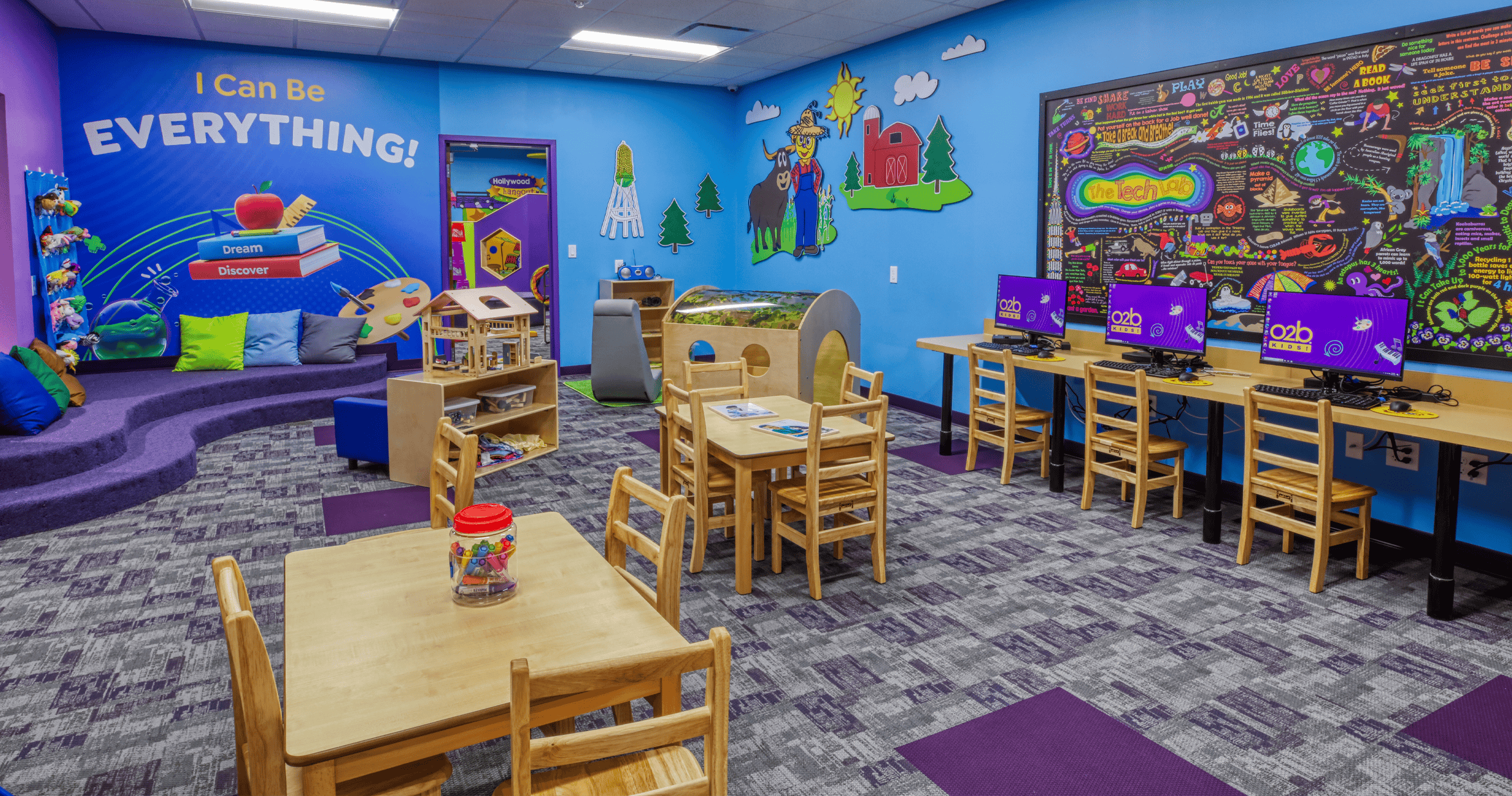 Colorful classroom with tables, chairs, computers, and a wall mural that says "I Can Be EVERYTHING!"
