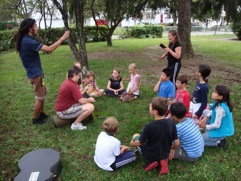 Adults and children sitting in a circle on grass outdoors