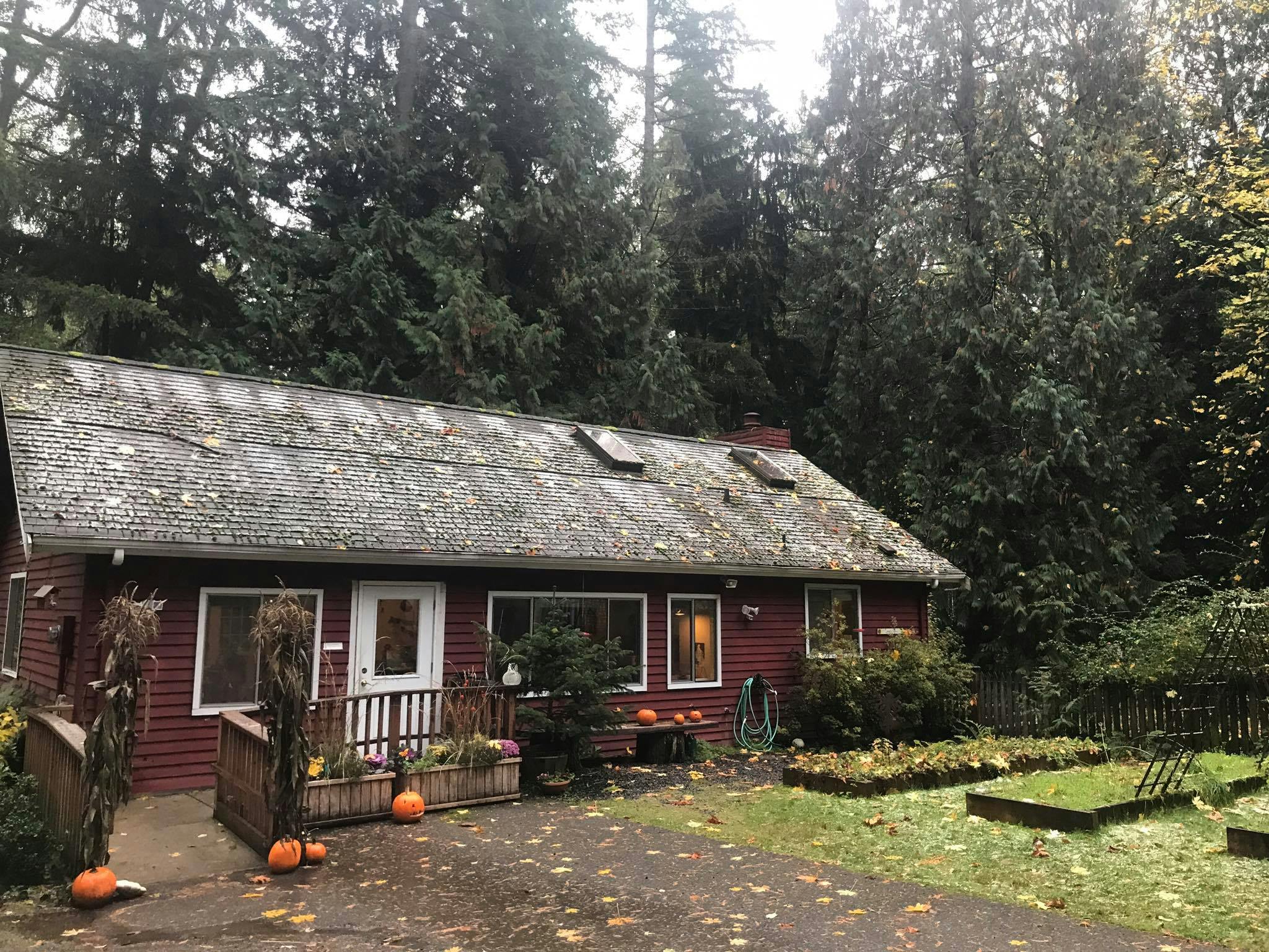 Red house with a gray roof and trees in the background