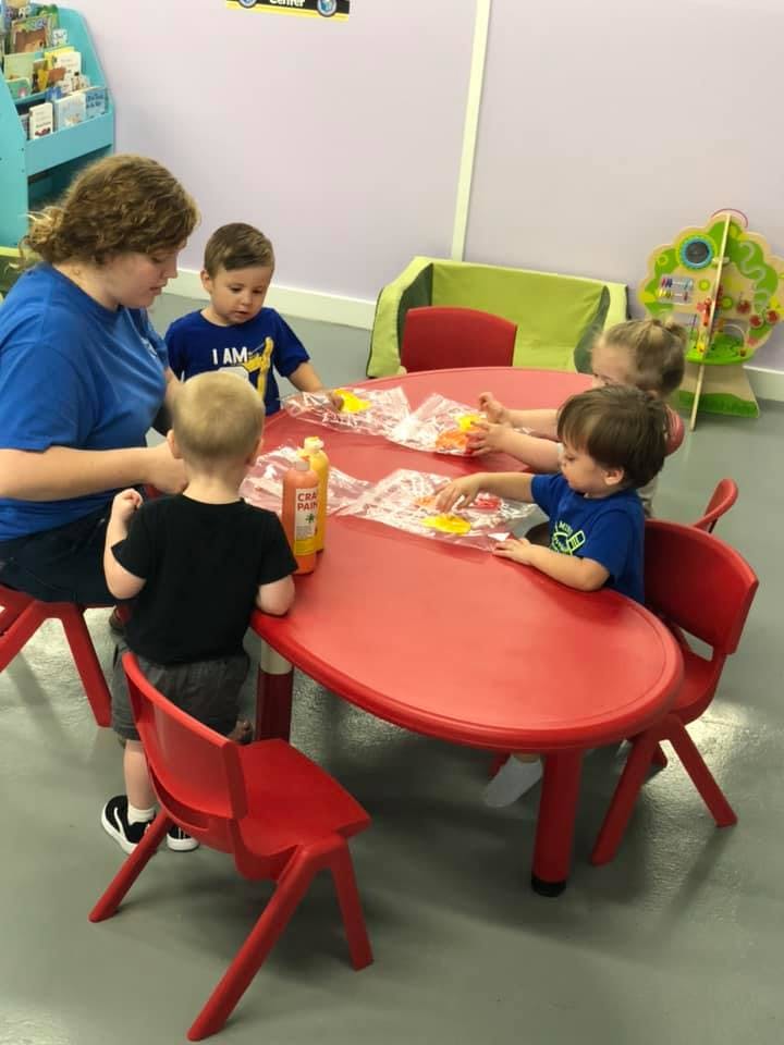 Adult and children at a red table in a classroom