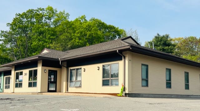 Exterior of a single-story building with light-colored walls and a dark roof