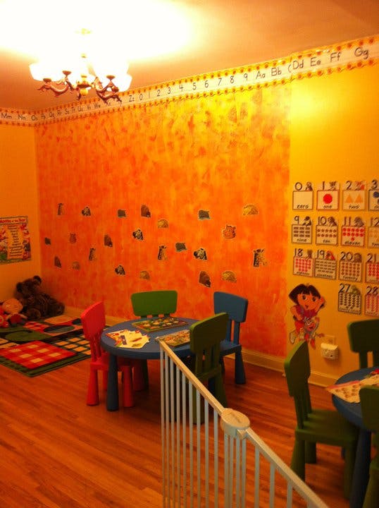 Classroom with small tables and chairs, alphabet and number charts on walls