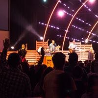 People in an audience with hands raised watching a band perform on stage