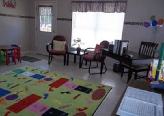 Room with a colorful rug, small table and chairs, and a desk with books