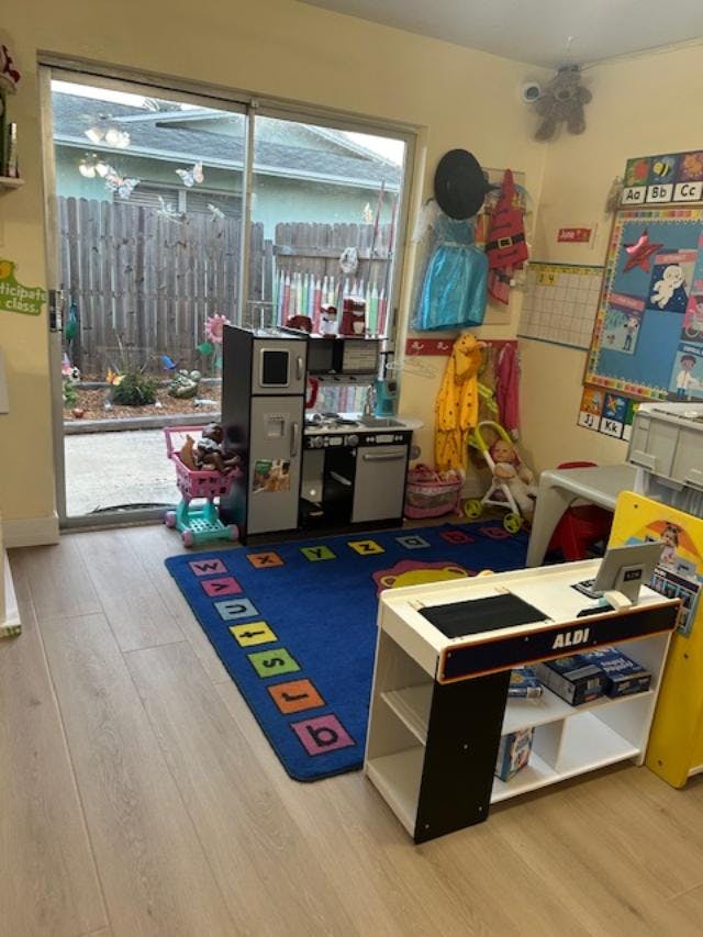 Playroom with toy kitchen, alphabet rug, and sliding glass door to backyard