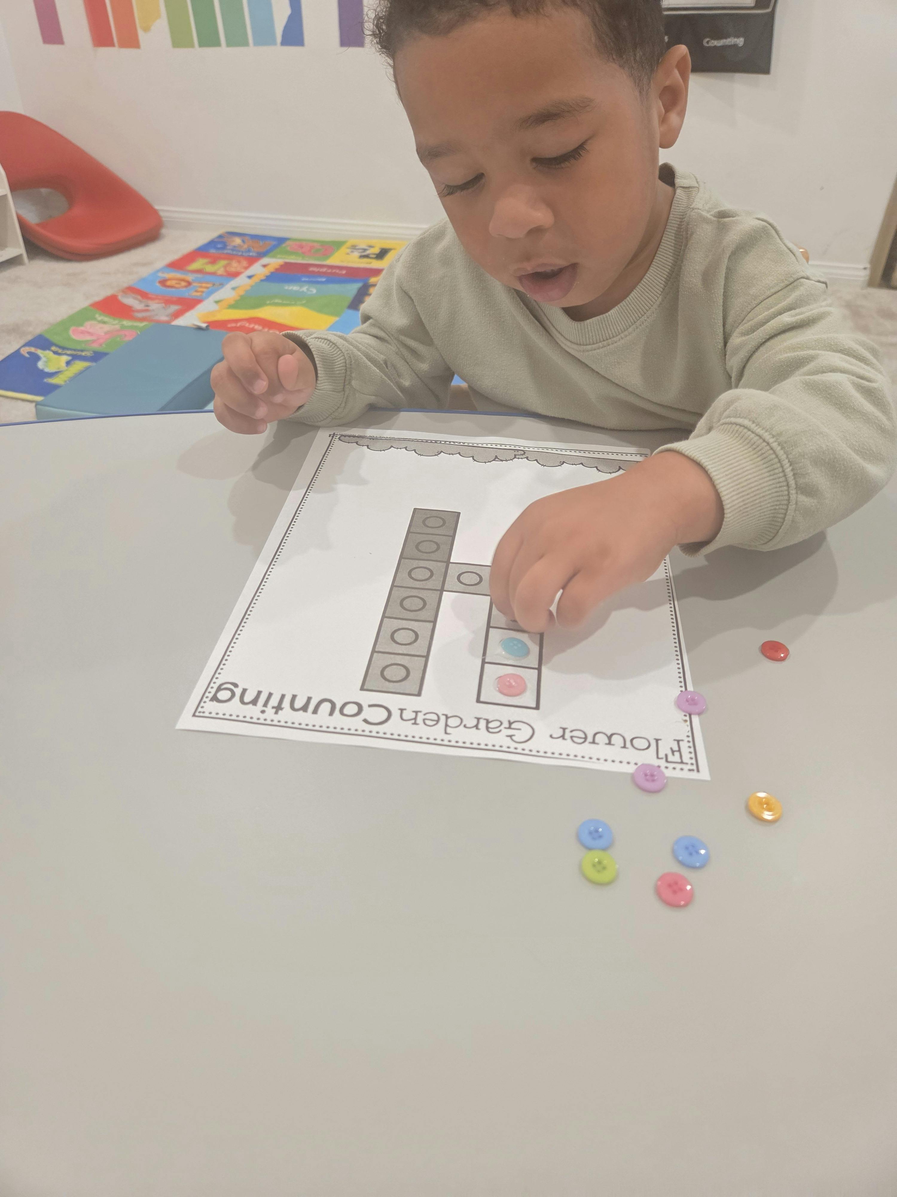 Child placing colorful buttons on a \"Flower Garden Counting\" sheet