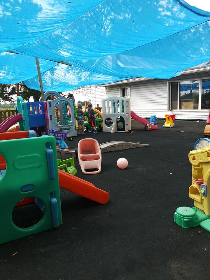 Outdoor playground with various colorful play structures under a blue canopy