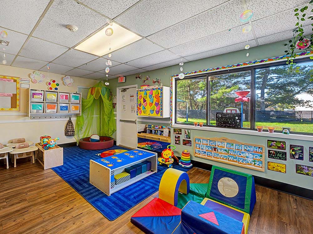 Colorful playroom with soft play items, educational decorations, and a large window