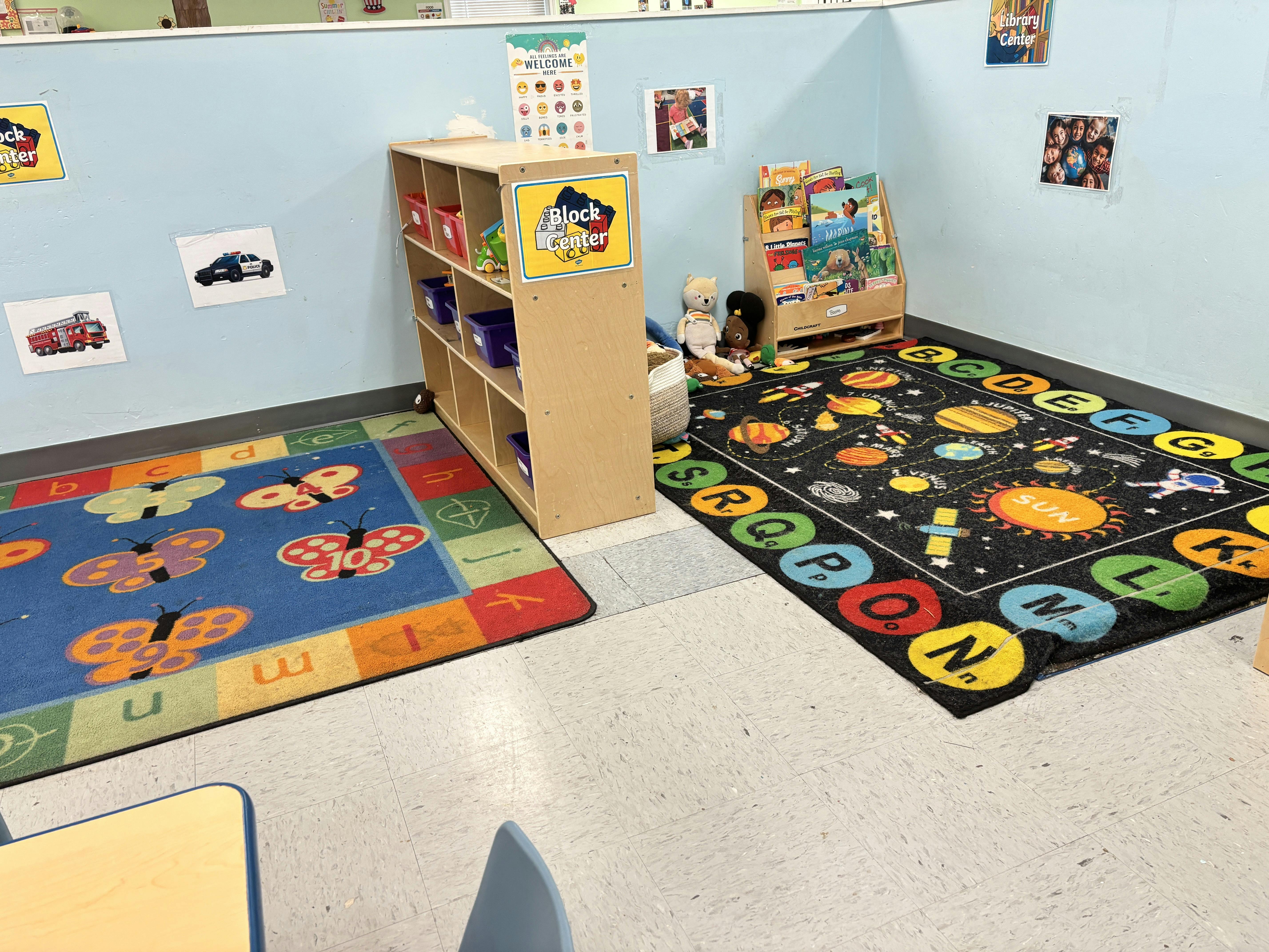 Classroom corner with a block center, book display, and alphabet rugs