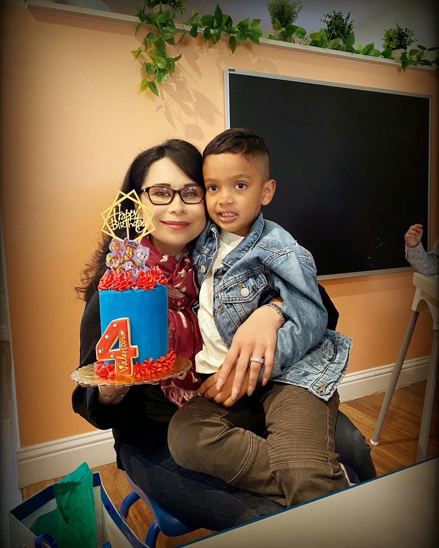 Person holding a child and a birthday cake with the number 4