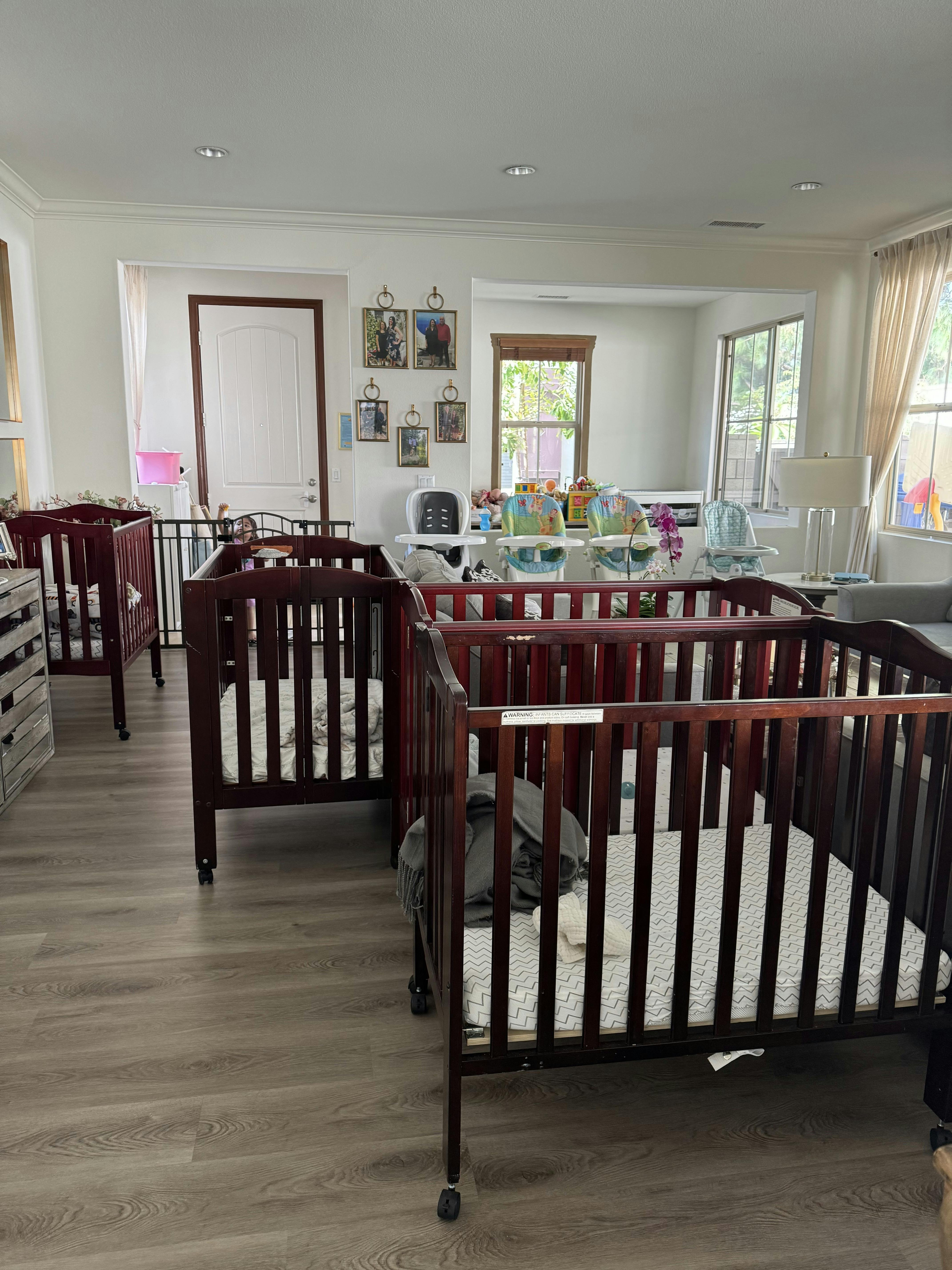 Multiple dark brown cribs with mattresses in a room with hardwood floors
