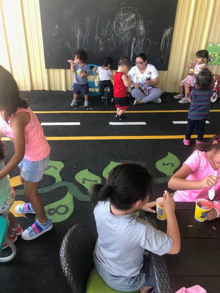 Children and an adult in a classroom with a chalkboard and floor markings
