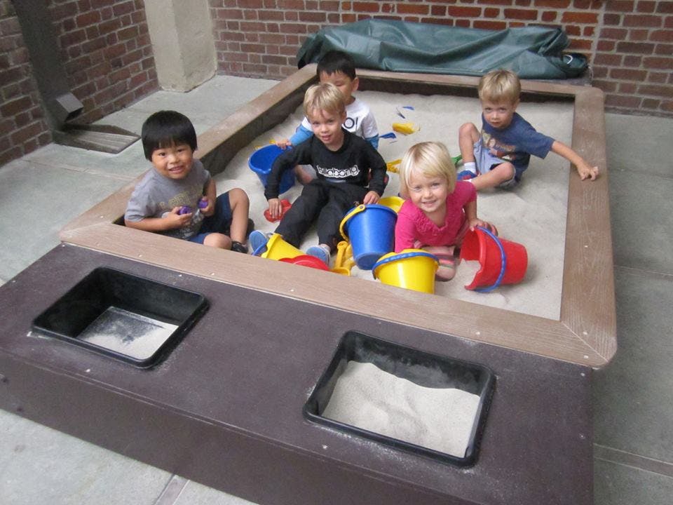 Children playing in a sandbox with buckets and shovels