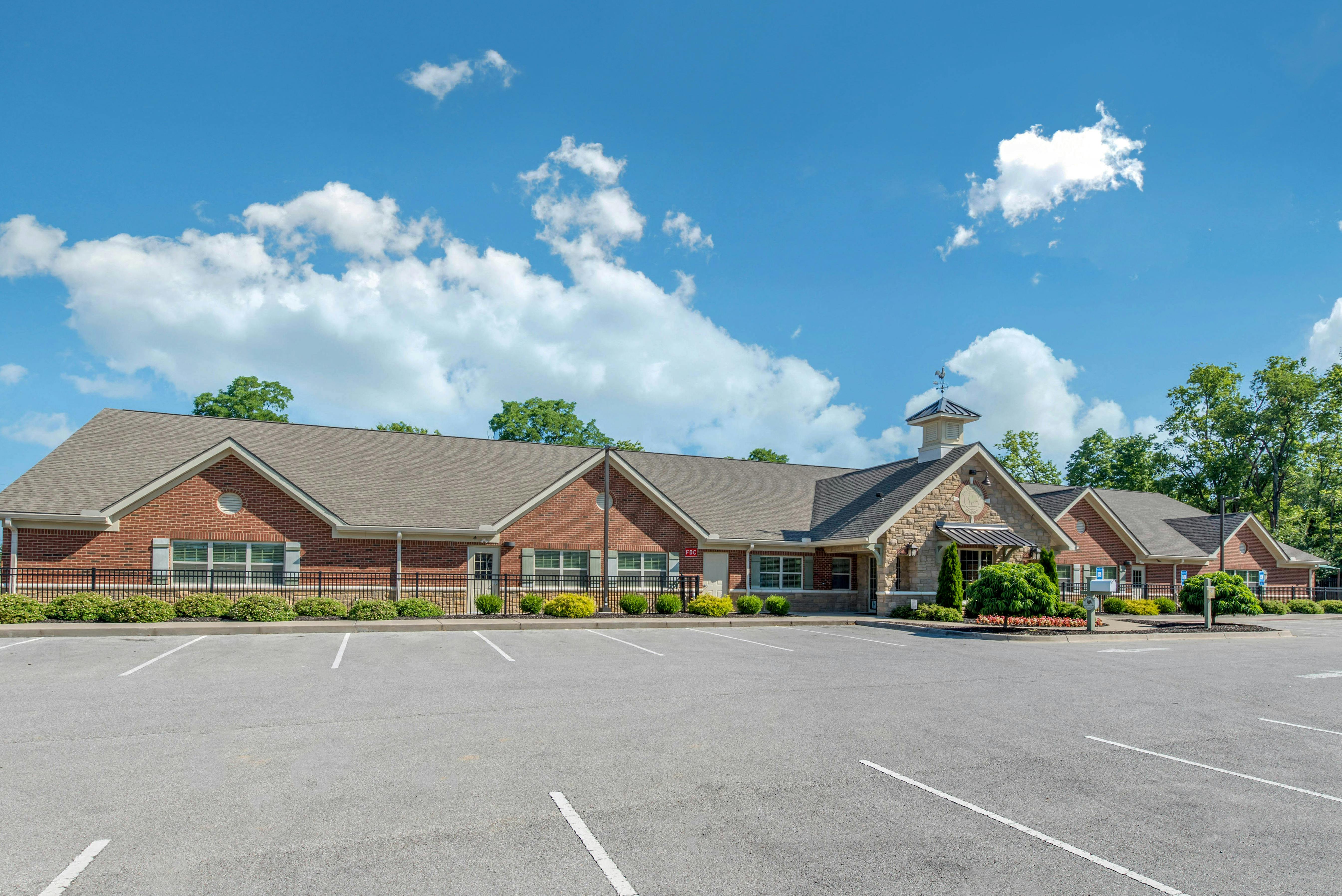 Brick building with stone entrance and parking lot in front