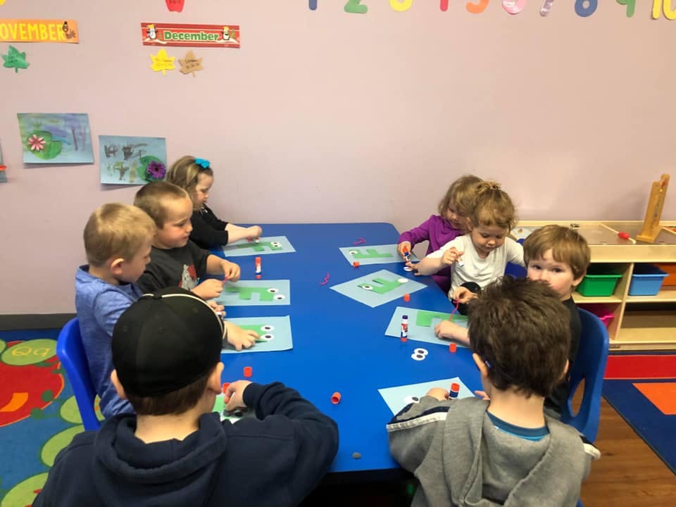 Children sitting around a blue table in a classroom