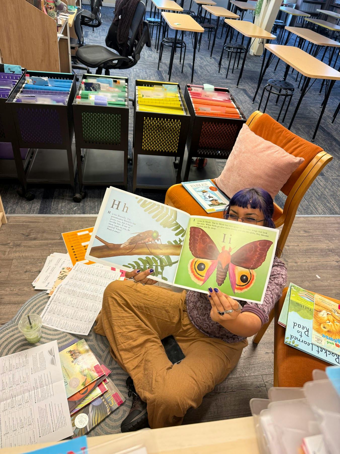 Person holding an open children's alphabet book featuring a horsefly and moth