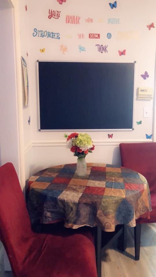 Table with a checkered tablecloth and a vase of flowers, red chairs